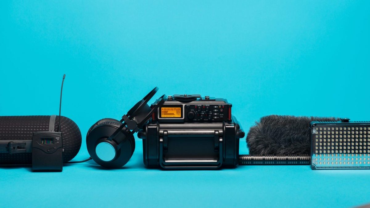 equipment for field audio recording on blue background. Windshield, shotgun microphone, radio system, recorder, boompole, portable case and headphones